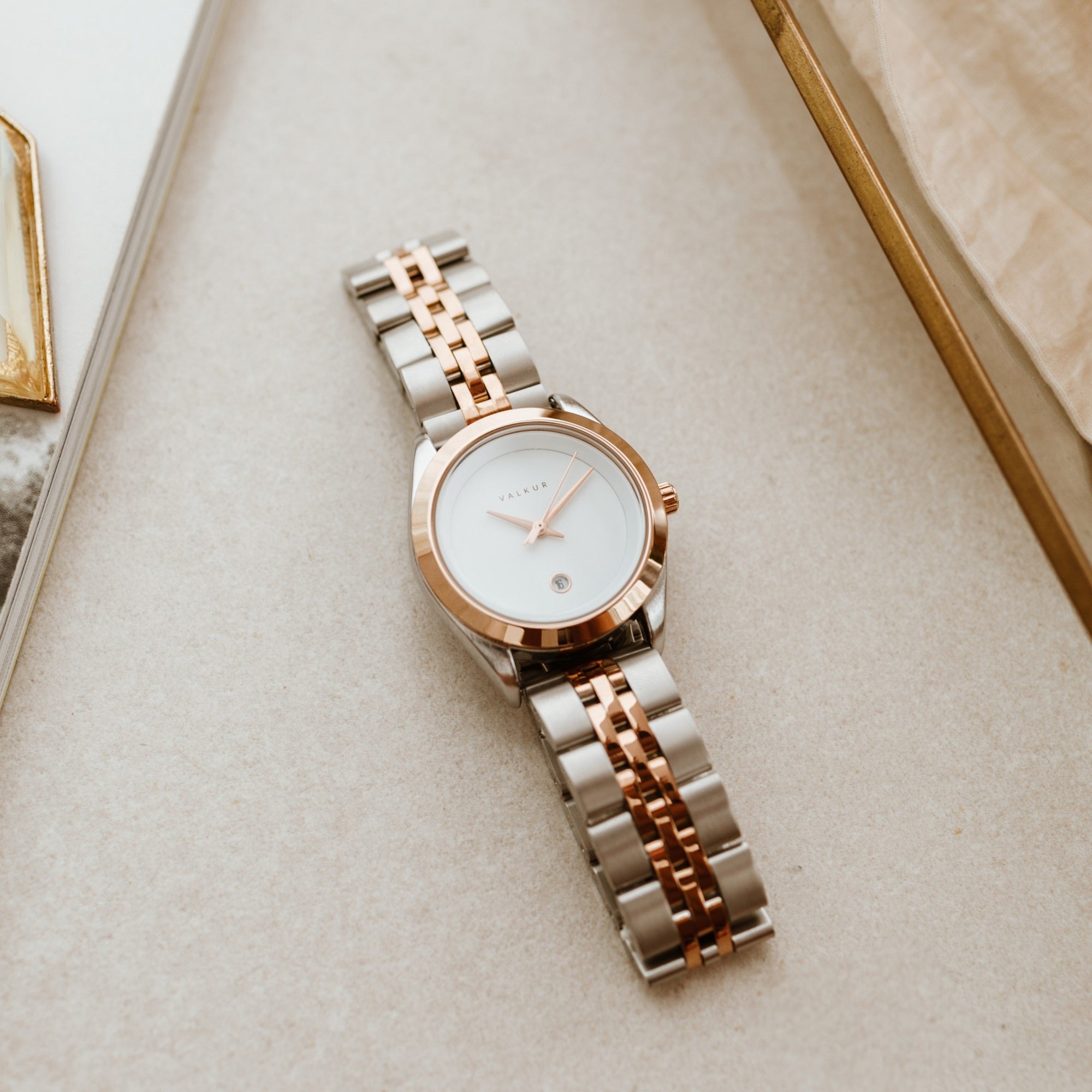 Reloj Valkur para mujeres modelo Agda de acero plateado con bisel dorado y fondo blanco
